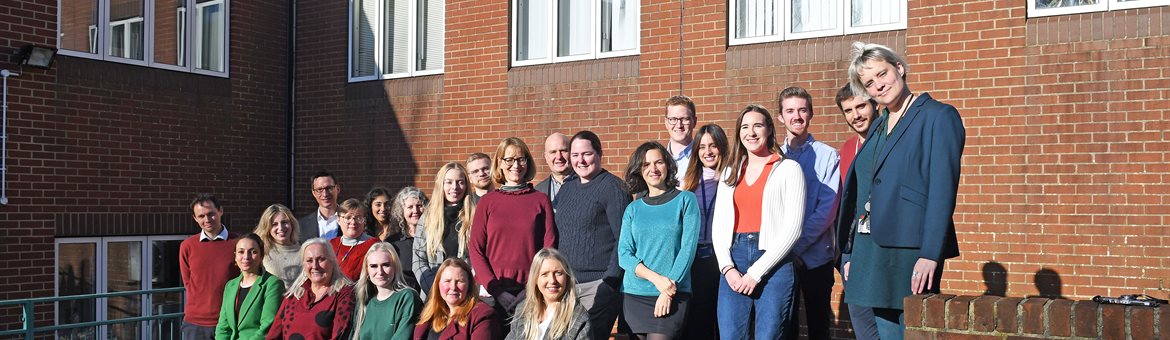 Image of neuroscience team stood and sat in front of building