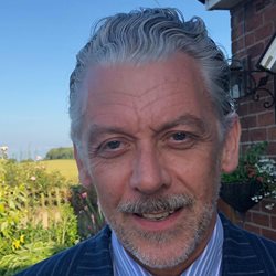 Peter Studley photographed outside a building on a sunny day