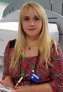 A photo of Sabina Dizdarevic in front of a scanning machine