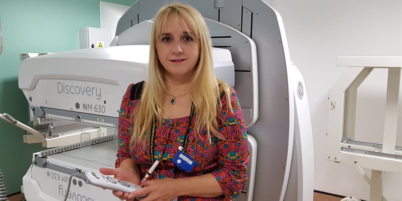 A photo of Sabina Dizdarevic in front of a scanning machine