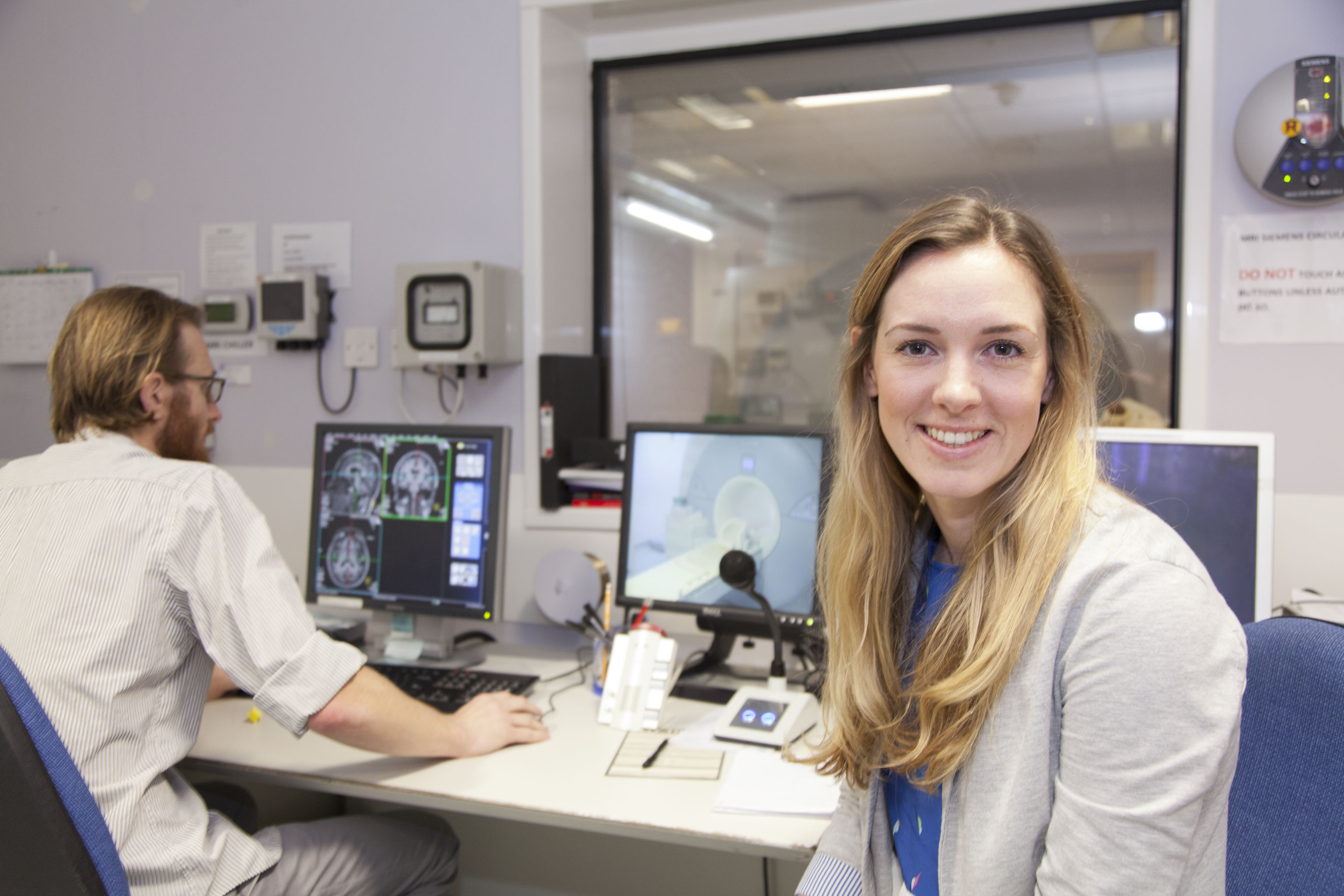 Fenella Prowse in the scanning control room at CISC, a staff member is looking at brain scans on a monitor