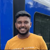 a global health alumni student named Abiman wearing a mustard t shirt in front of a blue train smiling