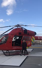 Alex Nye standing next to a helicopter