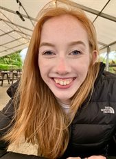 Olivia Tolson smiling sitting underneath an outside canopy