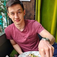 BSMS student Peter Preston leaning on a window eating food with a green curtain behind him