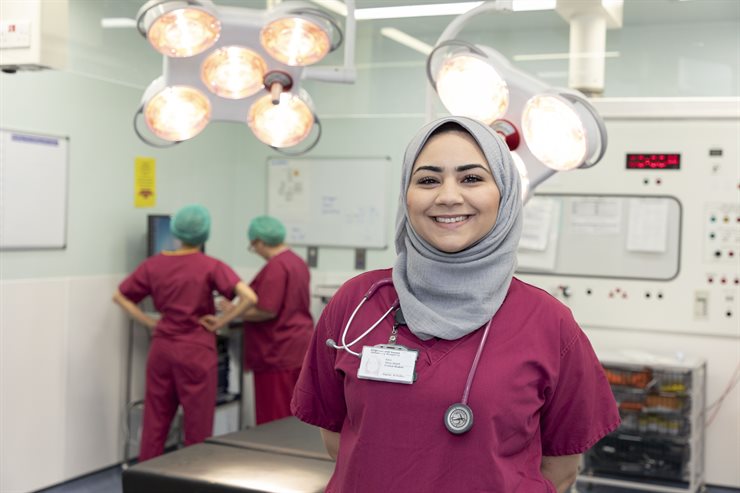 Sara Abou Sherif standing in the lecture theatre in scrubs, two staff in background