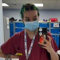 A student called Willow Neal taking a photo on her phone in front of a mirror wearing purple scrubs with a blue facemask. Blue lockers are in the background, showing she is about to go in to a hospital setting