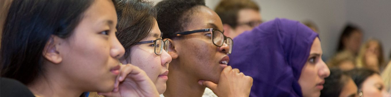 three students intently listening to lecturer