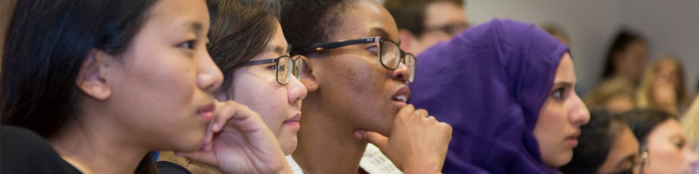 three students intently listening to lecturer